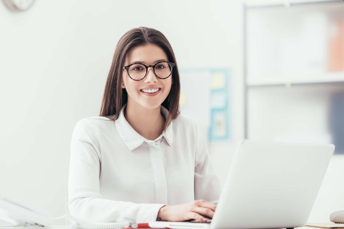 Smiling businesswoman with crossed arms in a bright, modern office environment.